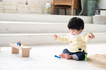 新築の様なきれいな部屋で木のおもちゃで一人遊びをする赤ちゃん　コピースペースあり	