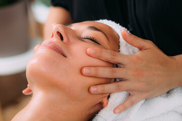 Obraz na płótnie Canvas Ayurveda Therapist Massaging Female Client Face with Ayurveda Oil