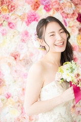 背景がバラの花でブライダルにも使えるかわいい花嫁さん7　縦向き笑顔左にコピースペースあり