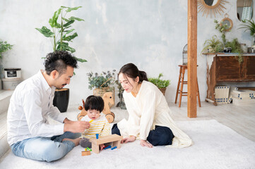 新築の様な白くて広い部屋で家族団らんの幸せな若いファミリー　広角　コピースペースあり