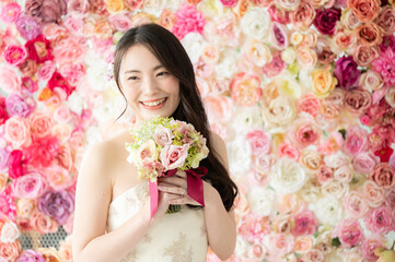 Obraz na płótnie Canvas 背景がバラの花でブライダルにも使えるかわいい花嫁さん1　右側にコピースペースあり