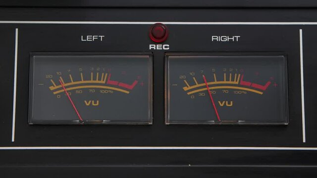 Analog VU meters on classic hi-fi reel-to-reel tape recorder. Displaying sound levels with arrow moving in sync to music. Dashboard close up.