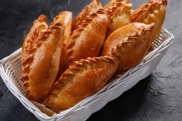 pies in a white basket on a dark background. © Artem Kudryavtsev