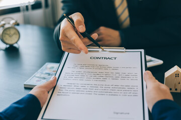 Buying a home or insurance deal, an insurance agent pointing a pen to those interested in renting a house, signing a contract, signing an agreement.