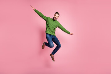 Full length body size view of attractive cheerful mature guy jumping having fun celebrating isolated over pink pastel color background