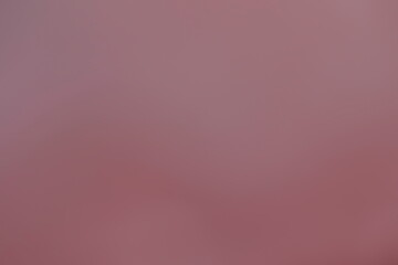 A blank reddish brown background with no text or letters of a wall, painted plaster or cardboard is...