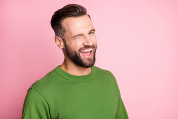 Close-up portrait of attractive cheerful glad content guy winking you isolated over pink pastel...