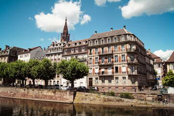 Fototapeta na wymiar Scenic view of beautiful houses at a river front and the bell tower of the Strasbourg Cathedral in the background.