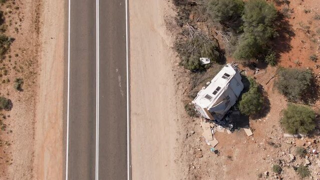 Aerial of camper caravan crashed on a highway accident in a desert rural area. Motorhome crashing event on the motorway. Travel and insurance concepts.