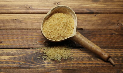Parboiled rice pile in calabash, gourd half on wooden plank table, background and texture