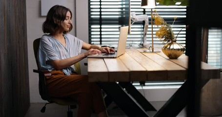 Young woman working on laptop in a cozy and style home office. Handheld shot. Stay home and happy working online from home concept - Powered by Adobe