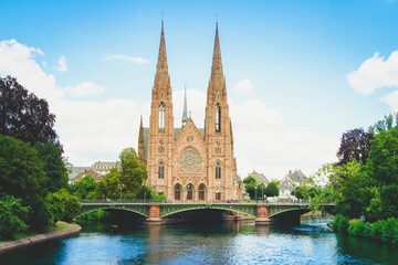 Fototapeta na wymiar Scenic view of St. Paul's Church and a bridge that leads over the Ill river in the city of Strasbourg, France under a clear blue sky.