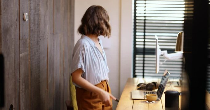 Young woman controlling room temperature with a smart thermostat at home. Medium shot. Smart home and smart heating system concept