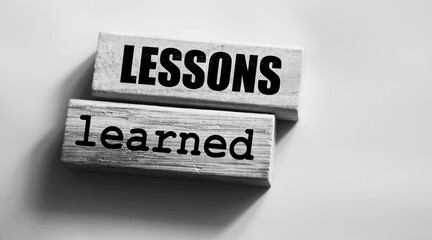 Lessons learned text on Wood blocks on pink. Business education concept.