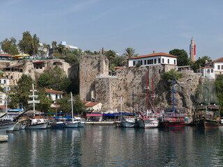 Fototapeta na wymiar Antalya, Turkey, October 24, 2020: Reflections of boats on the waters of Antalya’s harbour with its steep, stone cliff walls.