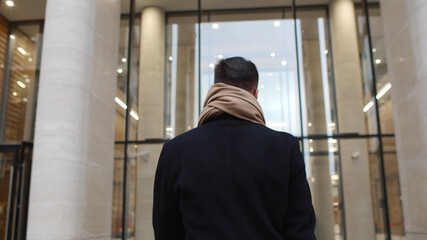 Back view of successful businessman entering business center