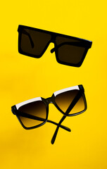 gafas de sol de moda colgando con fondo amarillo