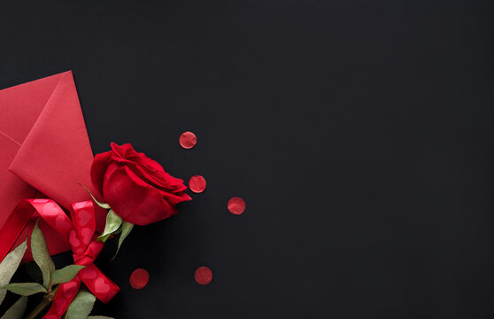 Valentines day gift card red envelop and red rose on black background with copy space, banner