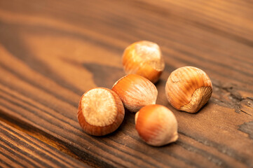 A few hazelnuts scattered on the wooden surface. Close-up, selective focus.