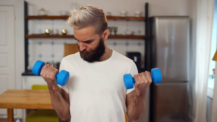 Hipster weak guy doing fitness training with dumbbells at home