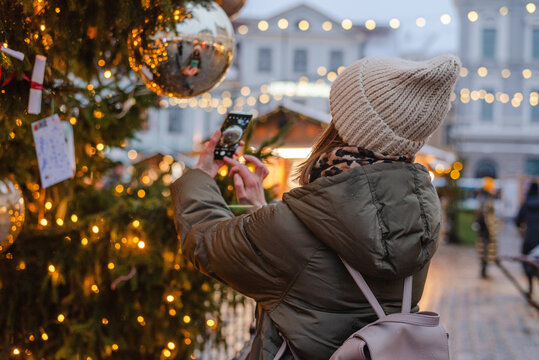 Woman in face mask taking photo on Christmas market in Tallinn, Estonia