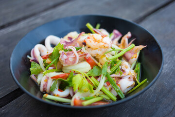 Spicy sea food (boiled shrimp and squid) is mixed with fresh vegetable (onion and celery) and spicy sauce as Thai food style.