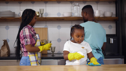 Happy afro-american family doing cleaning at kitchen together