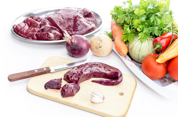 Raw liver and vegetables on a table close-up