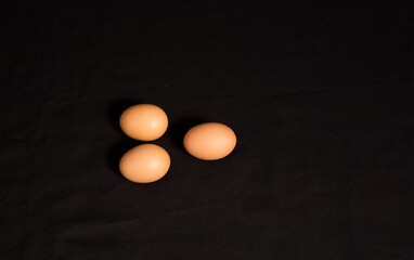 High angle shot and top view of three eggs isolated on black background. 