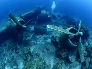 scuba divers exploring airplane wreck underwater taking photos of c47 dakota airplane engine 
