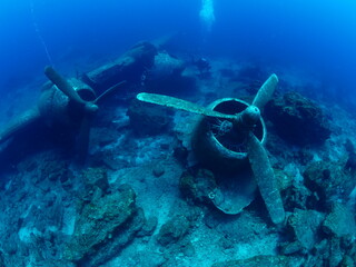 Naklejka na ściany i meble scuba divers exploring airplane wreck underwater taking photos of c47 dakota airplane engine 