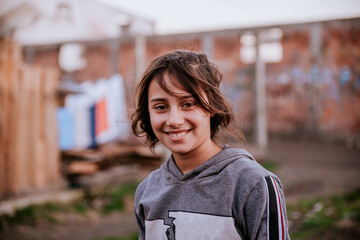 A portrait of a beautiful smiling gypsy woman in a Roma settlement looking at the camera - obrazy, fototapety, plakaty