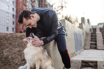 trendy guy with emotion playing with his dog on the outside