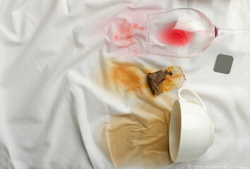 Top view of fallen glass of wina, cup of coffee and spot from tea bag on the white tablecloth.Empty space