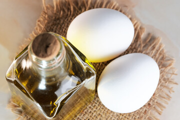 White raw eggs lie next to olive oil