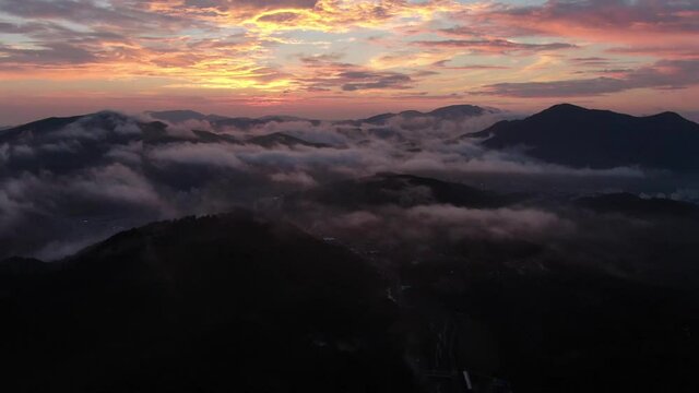 a drone flying over the clouds at dawn