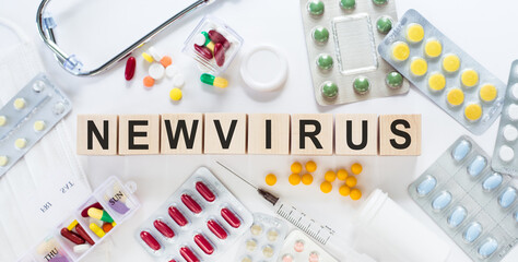 NEWVIRUS medicine word on wooden blocks on a desk. Medical concept with pills, vitamins, stethoscope and syringe on the background.