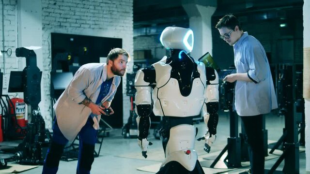 Male engineers are operating a cybernetic bot with gadgets