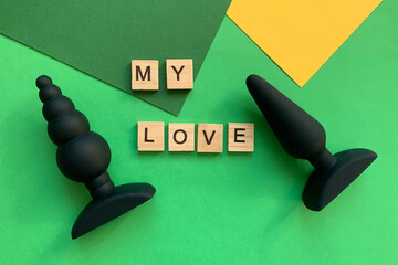 Sex toys. Two black butt plags on a green background. Inscription MY LOVE. Useful for adult, sex...