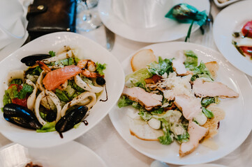 Serves dinner on a festive table. Food, Salads, Meat, Fish Meals. Festive table at wedding banquet. Decor. Details.