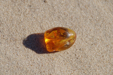 polished orange Baltic amber on sand