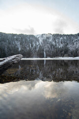 Verschneite Berge spiegeln sich in Bergsee. Gefrorener See im Winter.