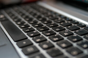 Laptop keyboard. White letters and black keys. Gray computer. Digital technologies