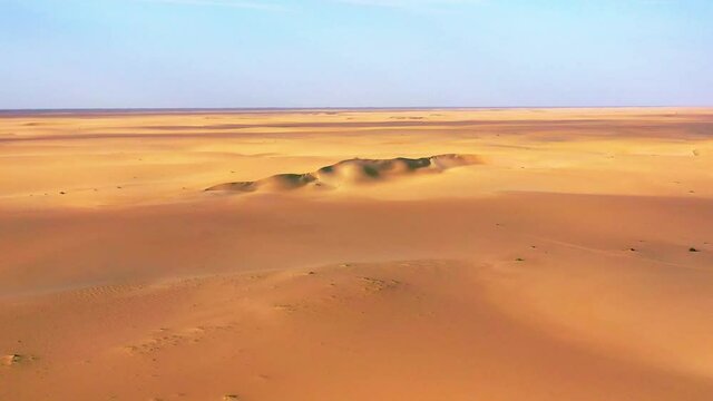 Aerial view towards a large sandbank, surrounded by wild, hot desert - dolly, drone shot