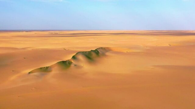 Aerial view towards a big sand dunes, in middle of endless, warm desert - tracking, drone shot
