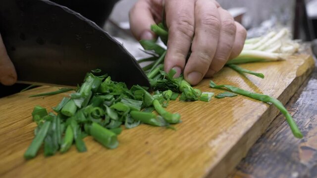 Finely chopped green onions with a hand-made chef's knife. Finely chop the green onions outdoors.