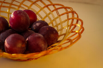Several ripe plum lie in a braided tray