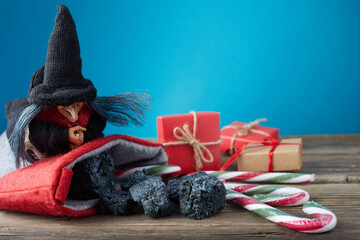 The Befana with sweet coal and candy on wooden background. Italian Epiphany day tradition.