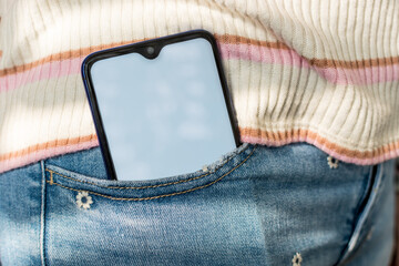 Close up Mobile phone with blank screen, in a jeans pocket. Focus on screen.