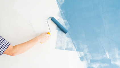 Man coloring wall blue with a roller